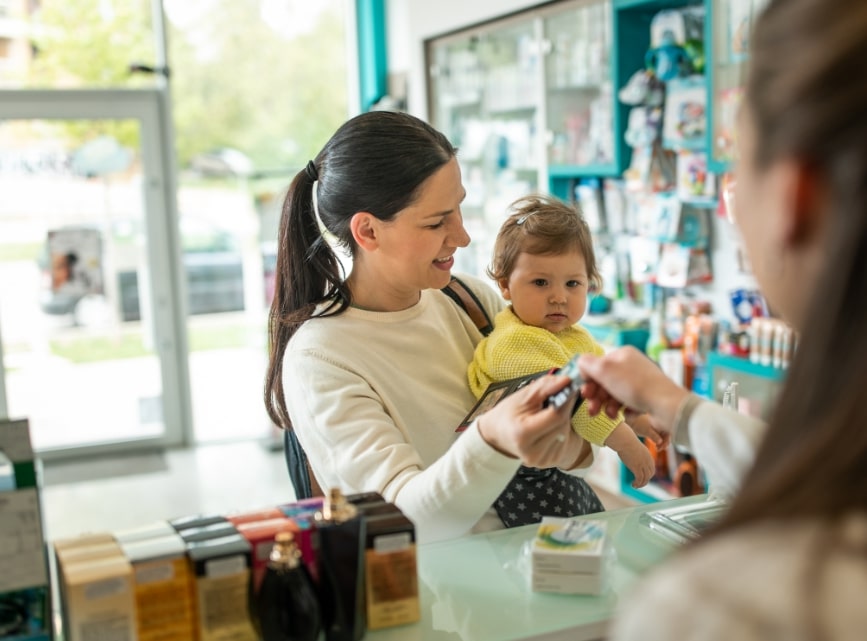 Woman with baby at pharmacy using HSA debit card